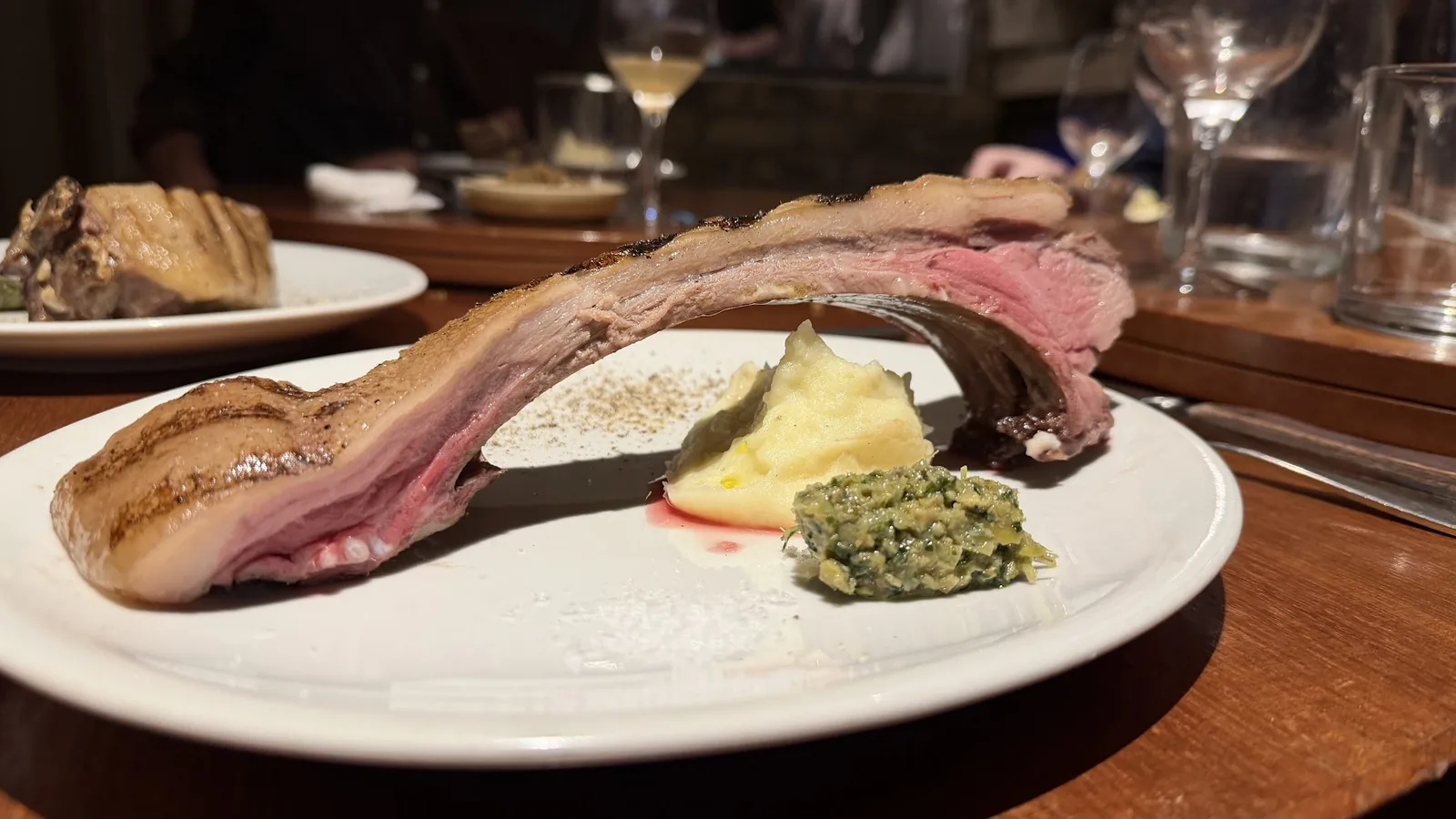 飲食店向けのジビエ流通を示す、骨付き肉とハーブの皿。